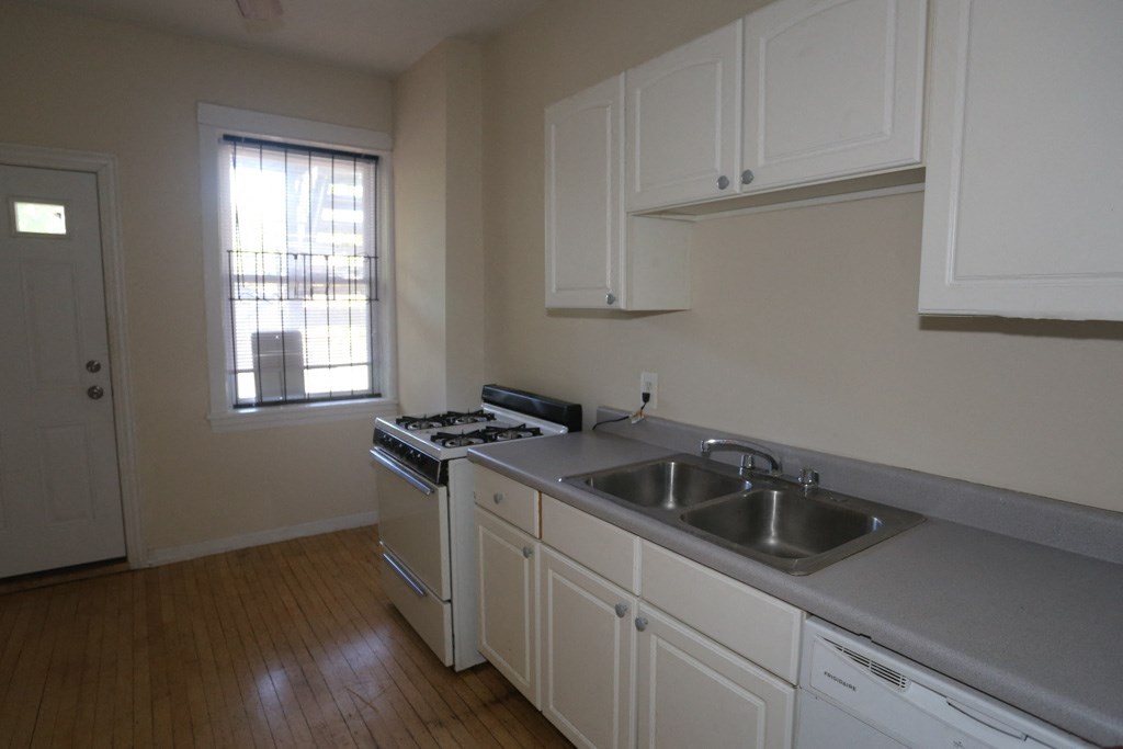 an empty kitchen with white cabinets and a stove and sink