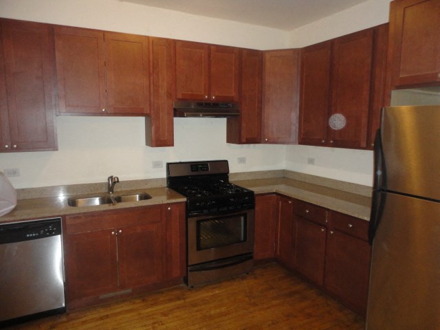 an empty kitchen with wooden cabinets and stainless steel appliances