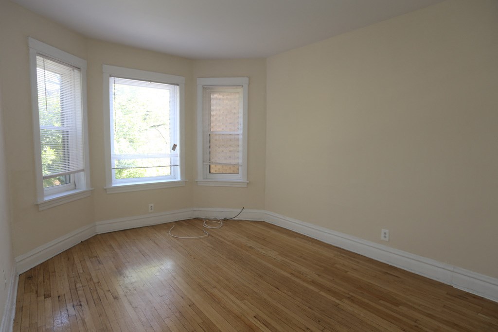 an empty room with a wooden floor and three windows
