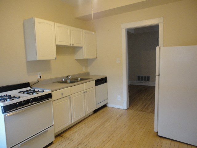 an empty kitchen with white appliances and a refrigerator