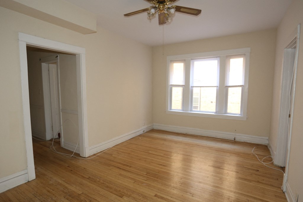 an empty living room with wood floors and a ceiling fan
