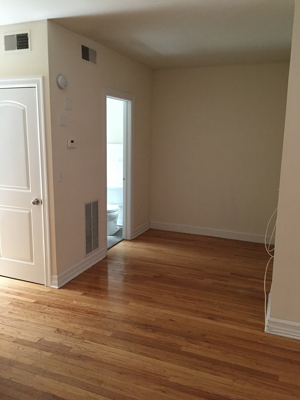 an empty room with wooden floors and a door to a bathroom