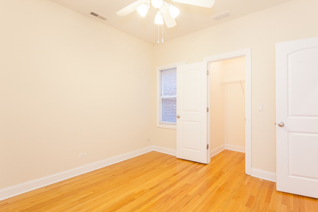 a bedroom with white walls and wood floors and a closet