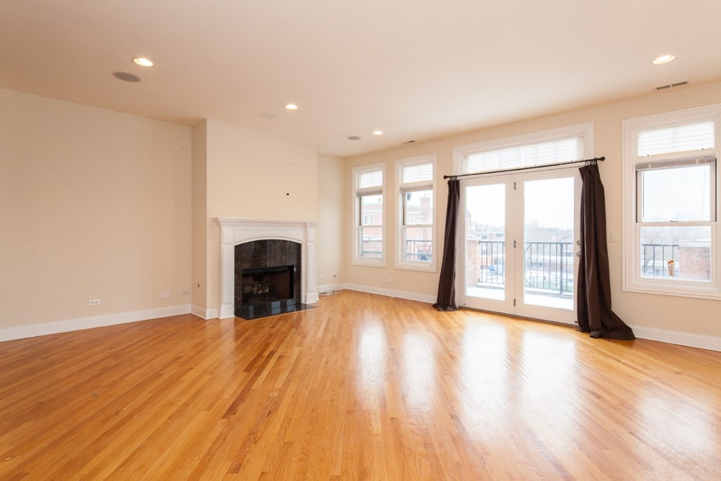 an empty living room with a fireplace and wooden floors