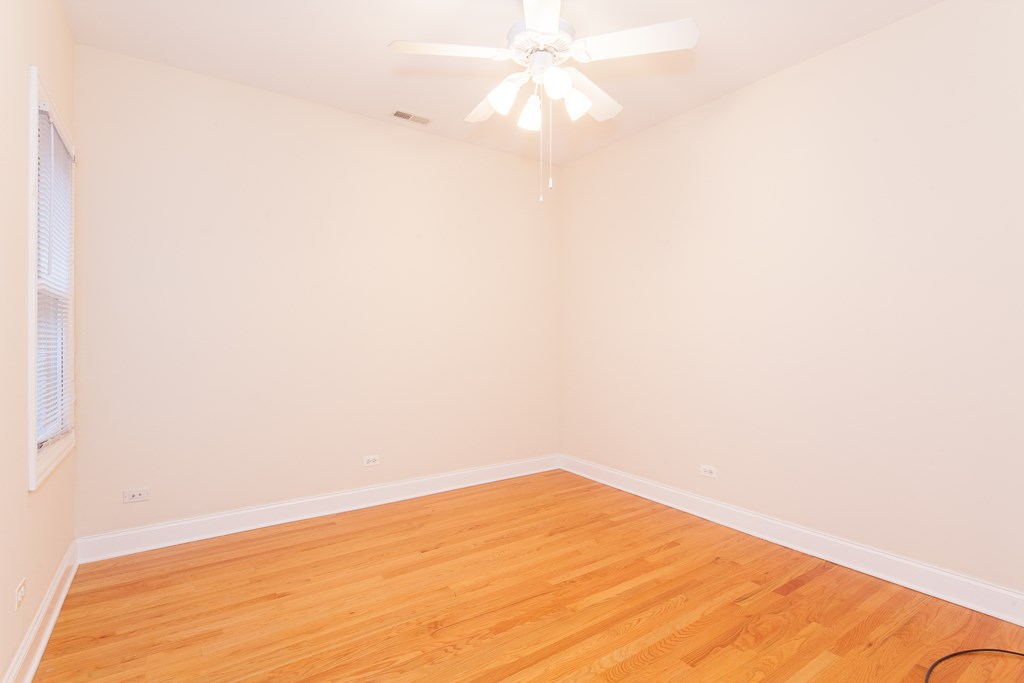 an empty room with wood flooring and a ceiling fan