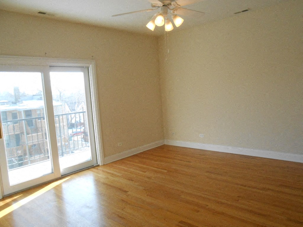 an empty living room with a ceiling fan and a balcony