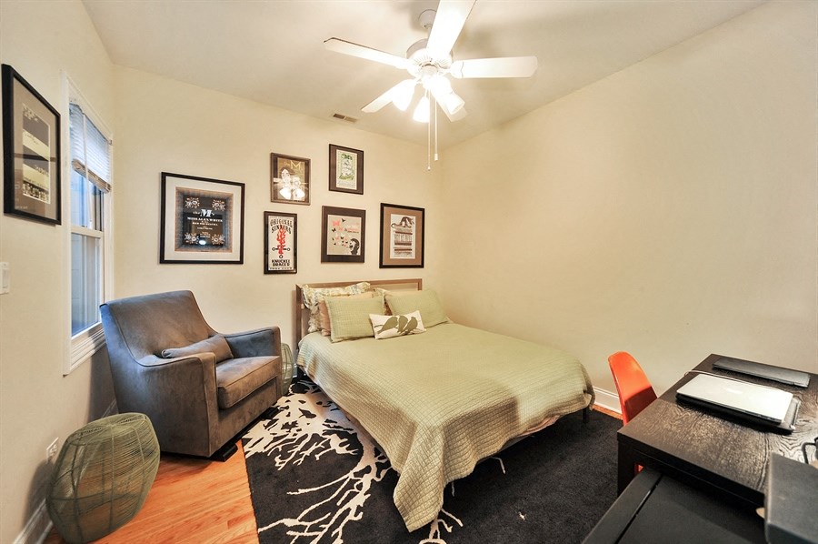 a bedroom with a bed and a chair and a ceiling fan