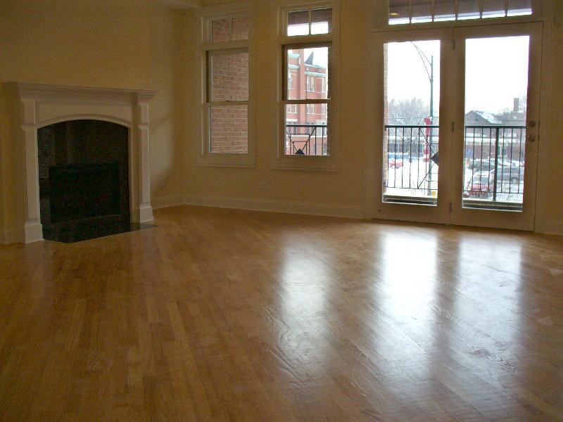 an empty living room with a fireplace and a wooden floor
