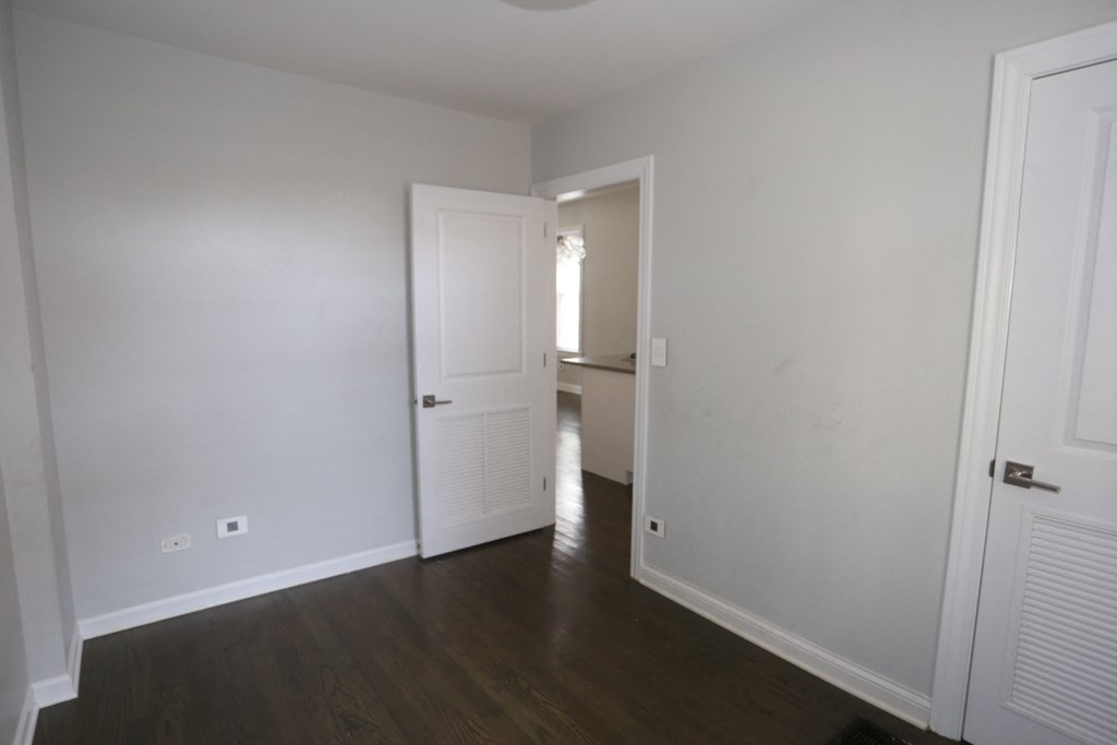 a bedroom with white walls and a door to a bathroom