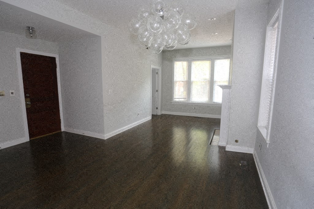 a empty living room with wood floors and a chandelier