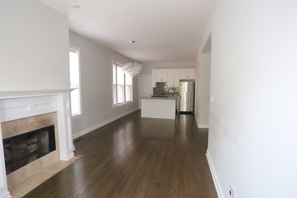 an empty living room with a fireplace and a kitchen