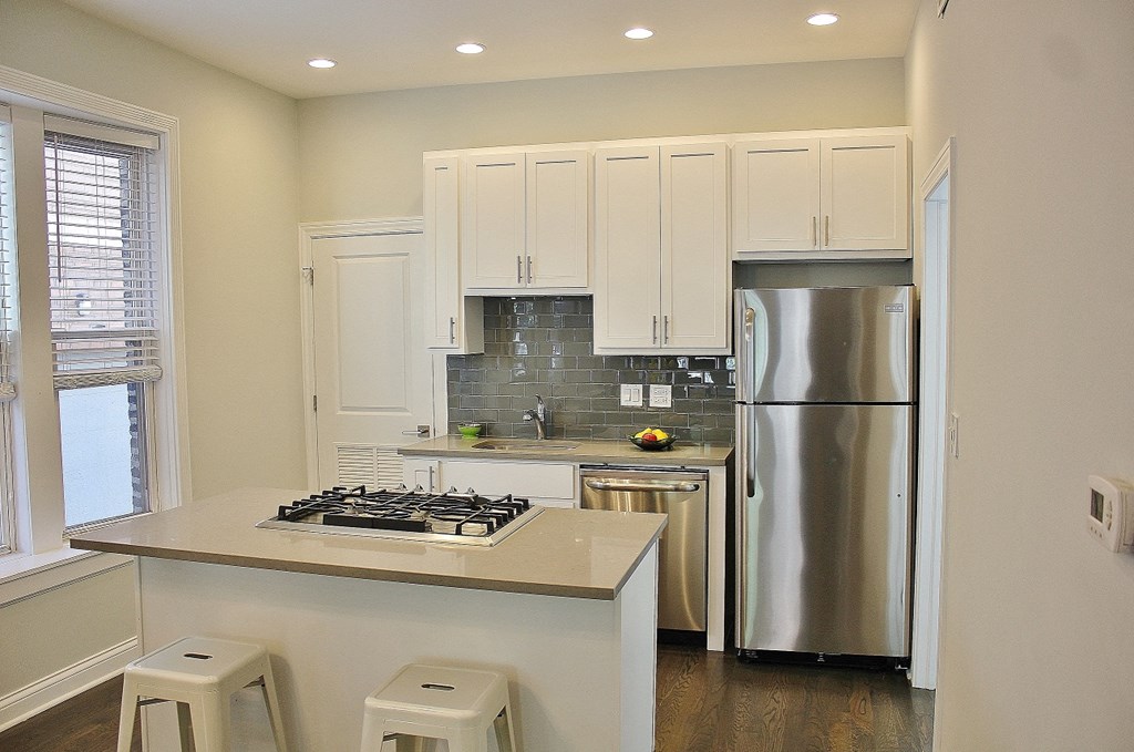 a kitchen with white cabinets and a stainless steel refrigerator
