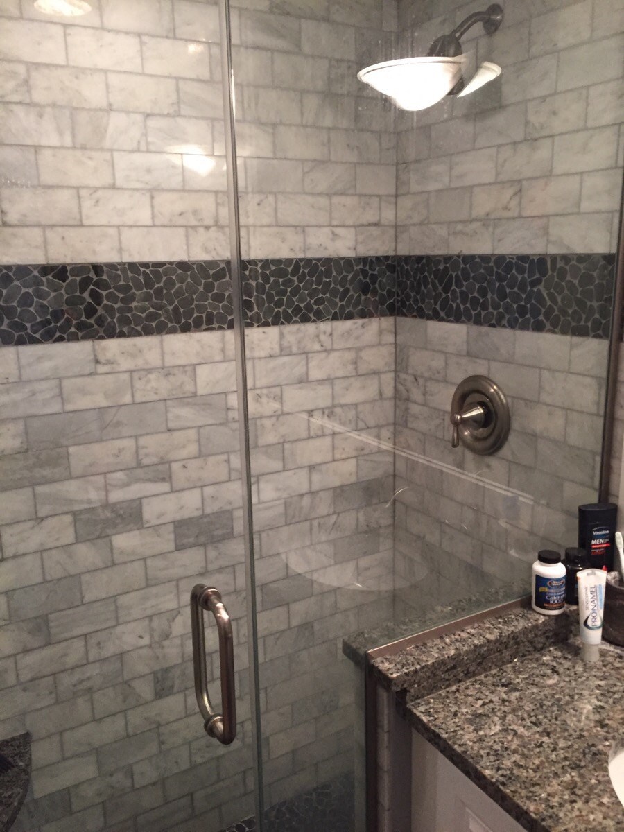 a bathroom with a shower and a granite counter top and a sink