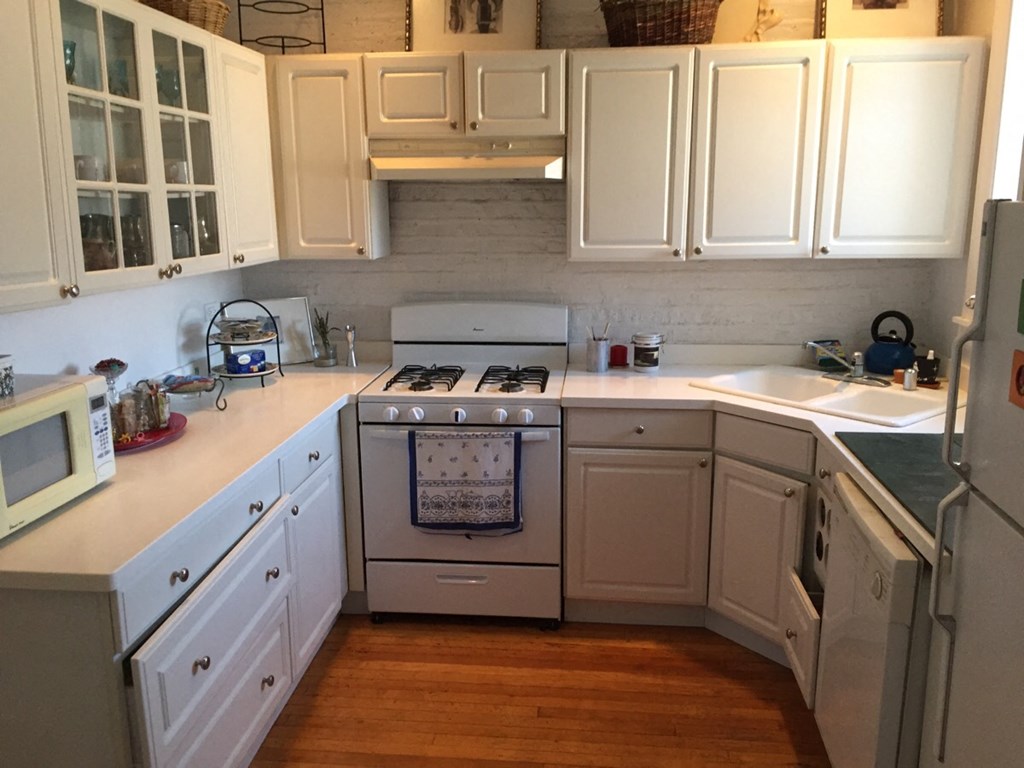 a kitchen with white cabinets and a stove and a sink