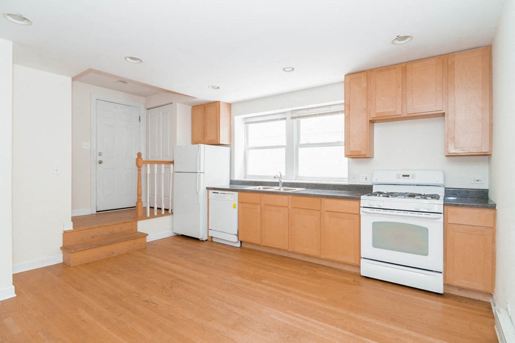 an empty kitchen with wooden floors and white appliances