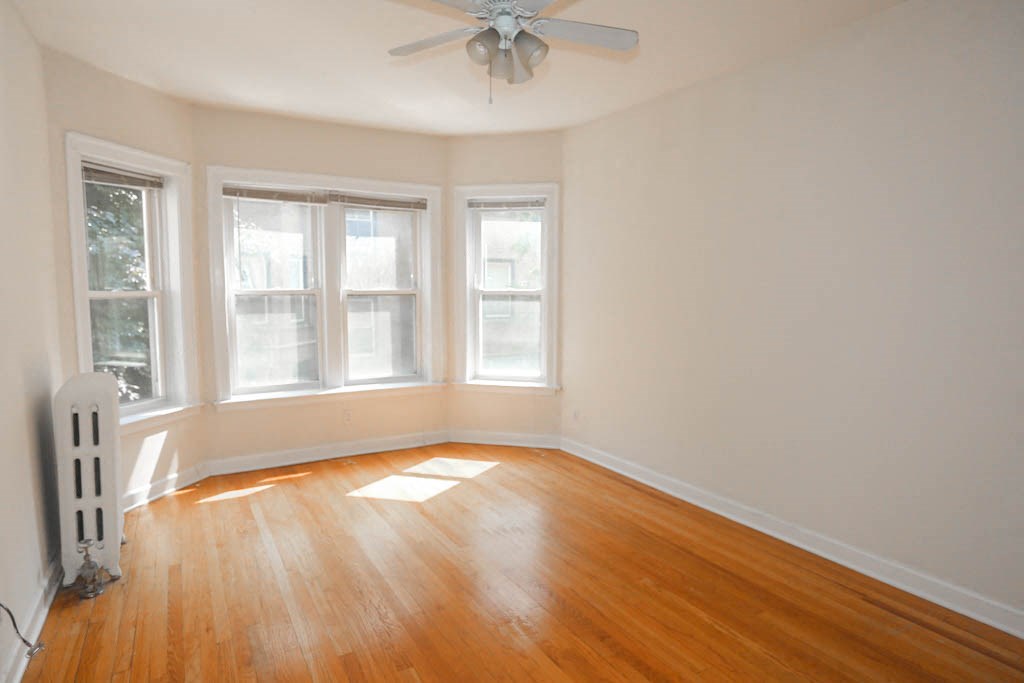 an empty room with wooden floors and a ceiling fan