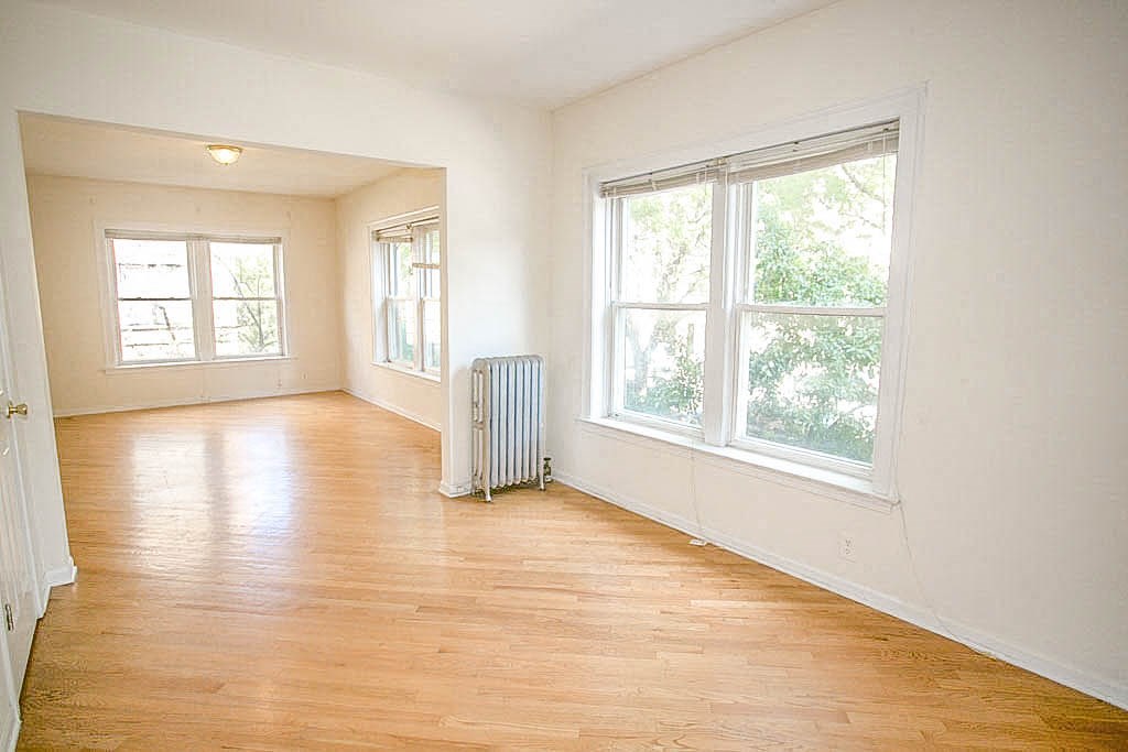 an empty living room with a wood floor and a radiator