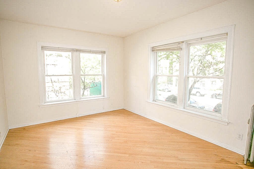 an empty room with a wooden floor and two windows