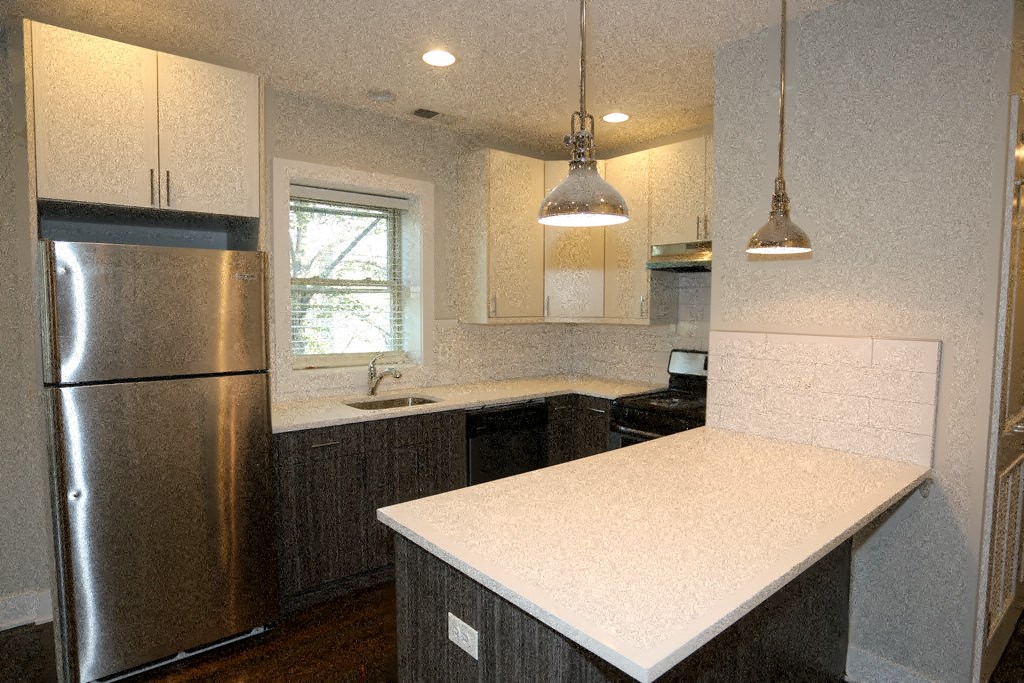 a kitchen with a white counter top and a stainless steel refrigerator