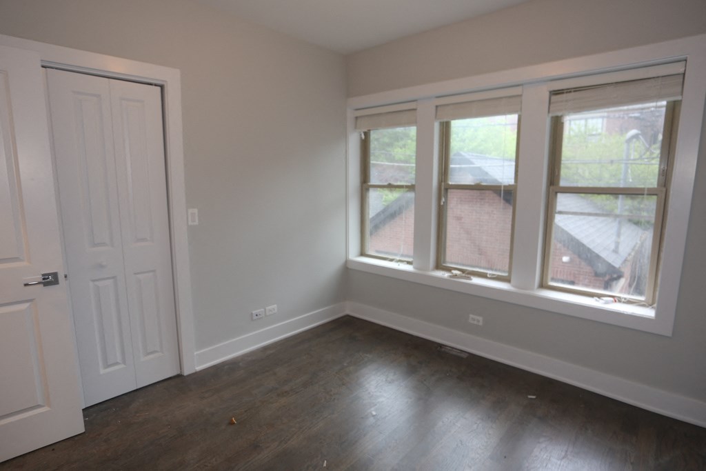 an empty bedroom with a door and three windows