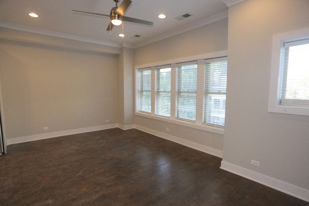 an empty living room with a ceiling fan and windows