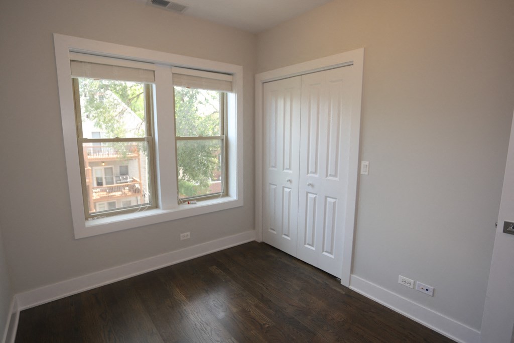 an empty bedroom with a door and two windows