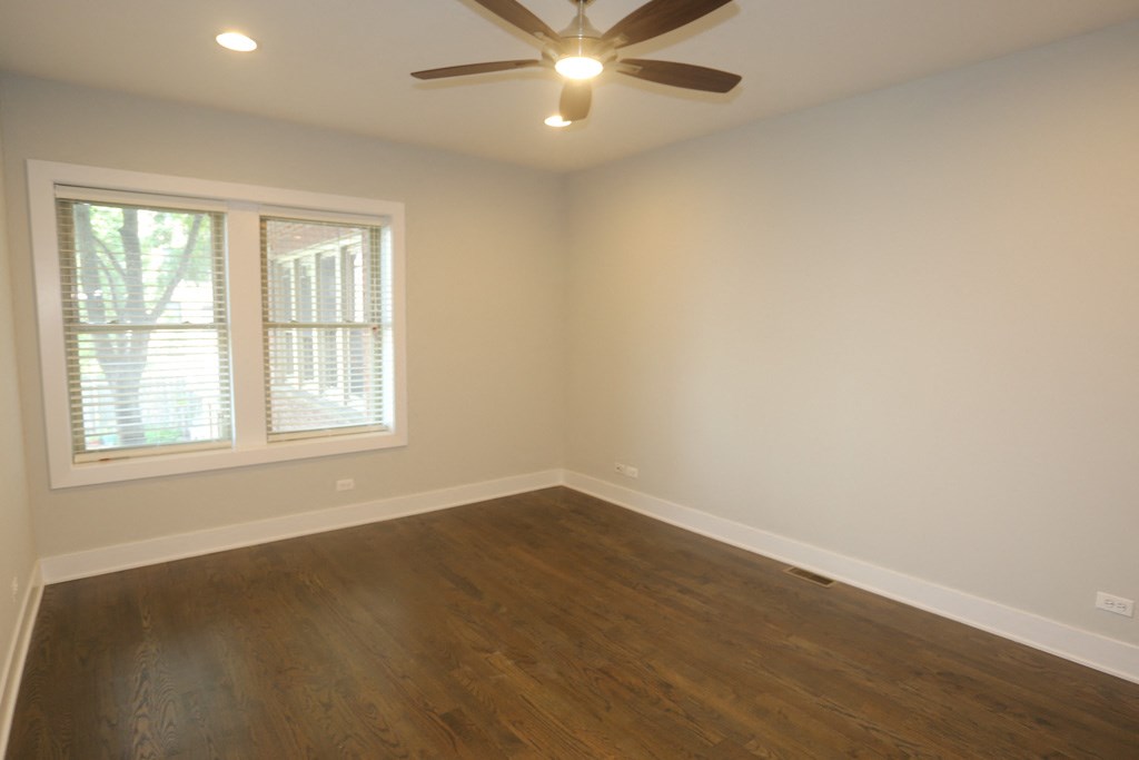 an empty living room with wooden floors and a ceiling fan