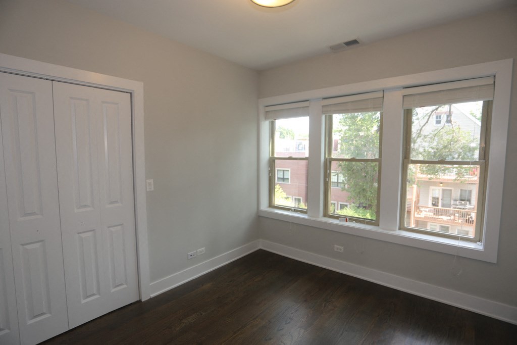 an empty bedroom with three windows and a door