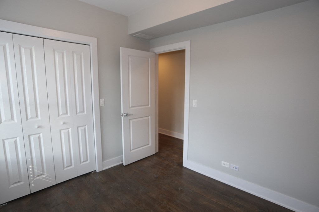 an empty room with two doors and a door to a closet