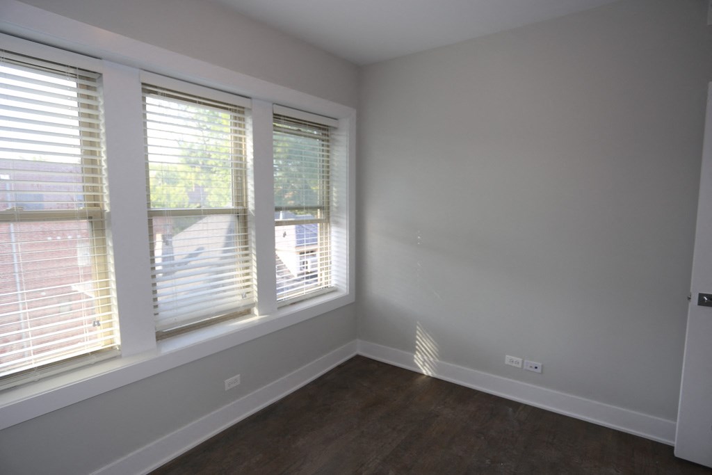 an empty room with three windows and a wooden floor