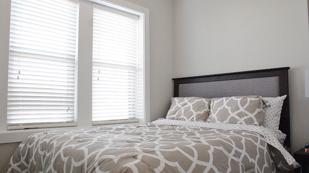 a bedroom with a bed and two windows