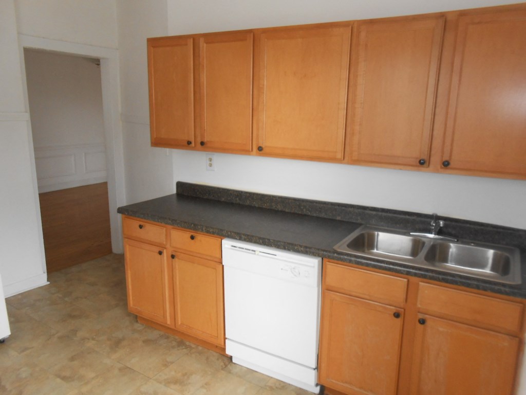 an empty kitchen with wooden cabinets and a white dishwasher