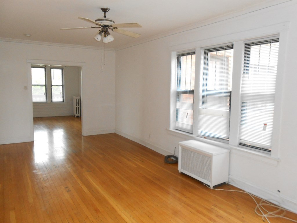 an empty living room with wood floors and a ceiling fan