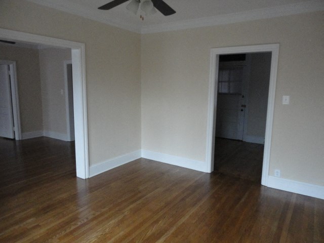 an empty living room with wooden floors and a ceiling fan