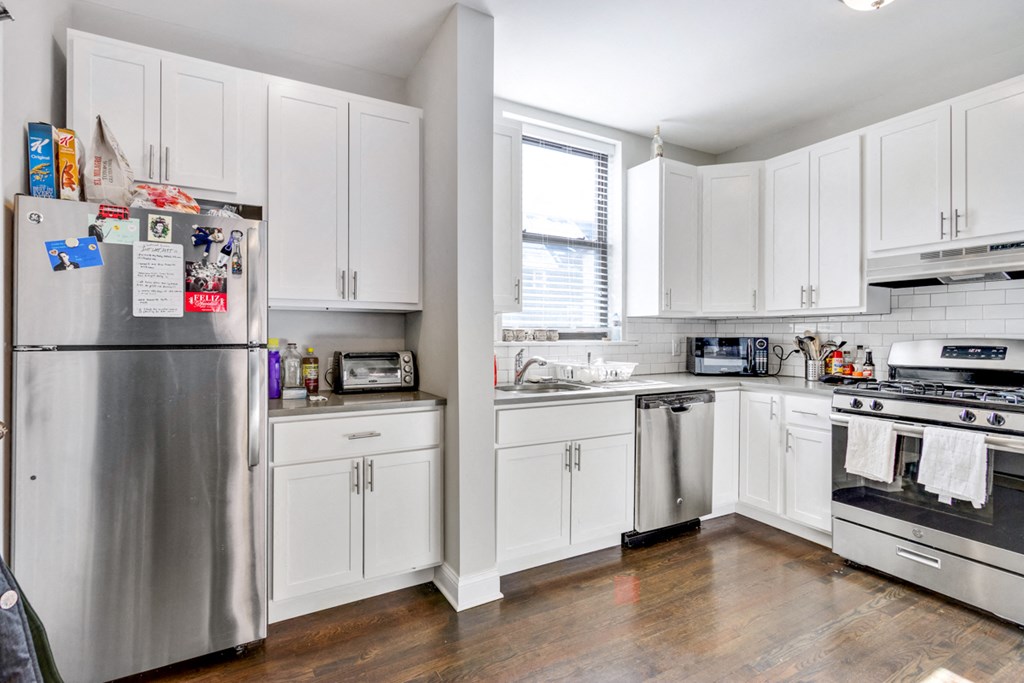 a white kitchen with stainless steel appliances and white cabinets