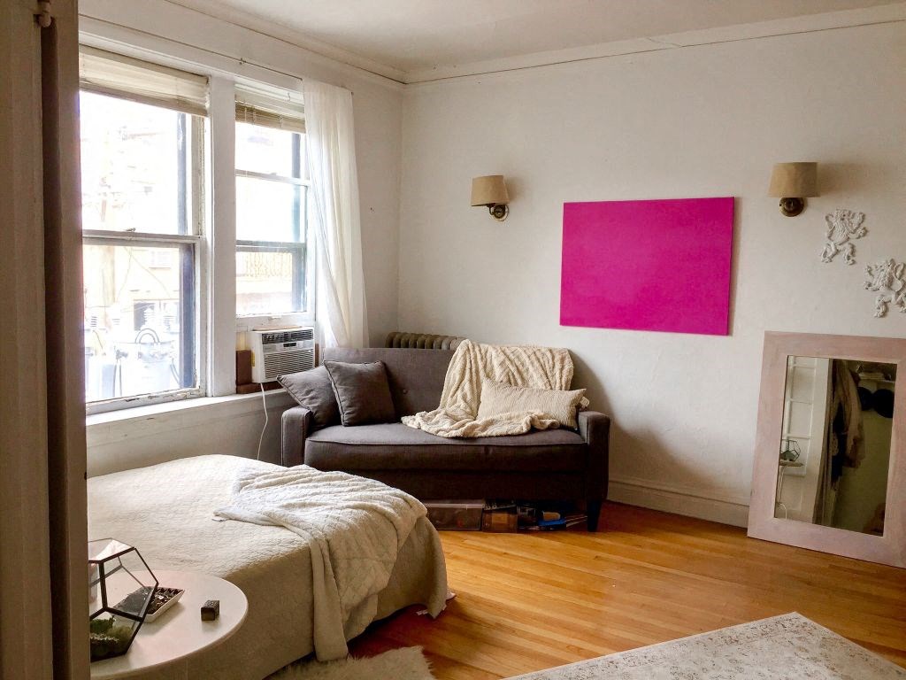 a living room with a couch and a pink painting on the wall