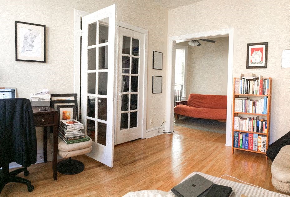 a living room with an open door and a book shelf