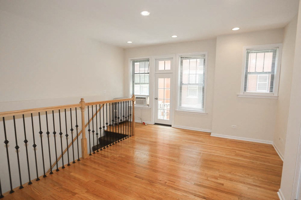a living room with a staircase and a door to a hallway with a wood floor