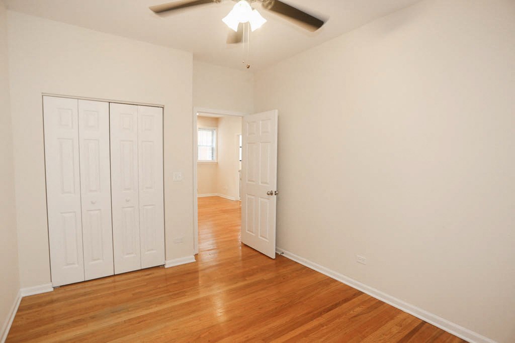 an empty living room with white walls and wood floors and a ceiling fan
