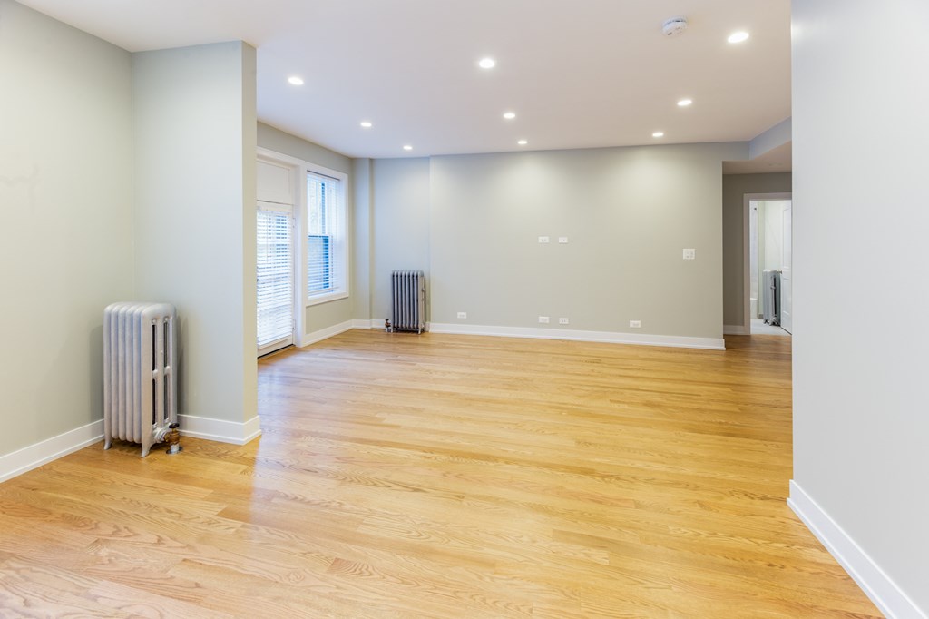 an empty living room with a wood floor and a radiator