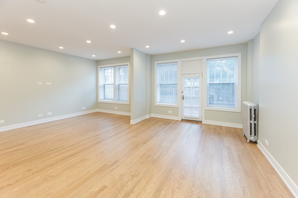 an empty living room with a hardwood floor and windows