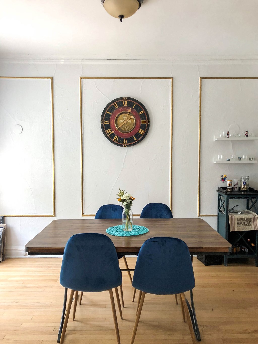 a dining room with a table and chairs and a clock on the wall