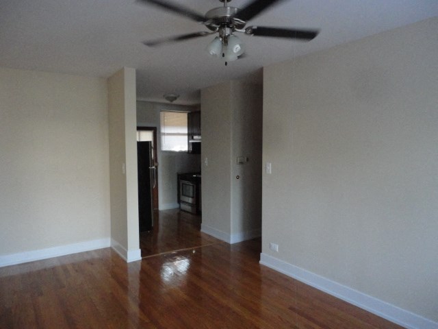 an empty living room with wooden floors and a ceiling fan