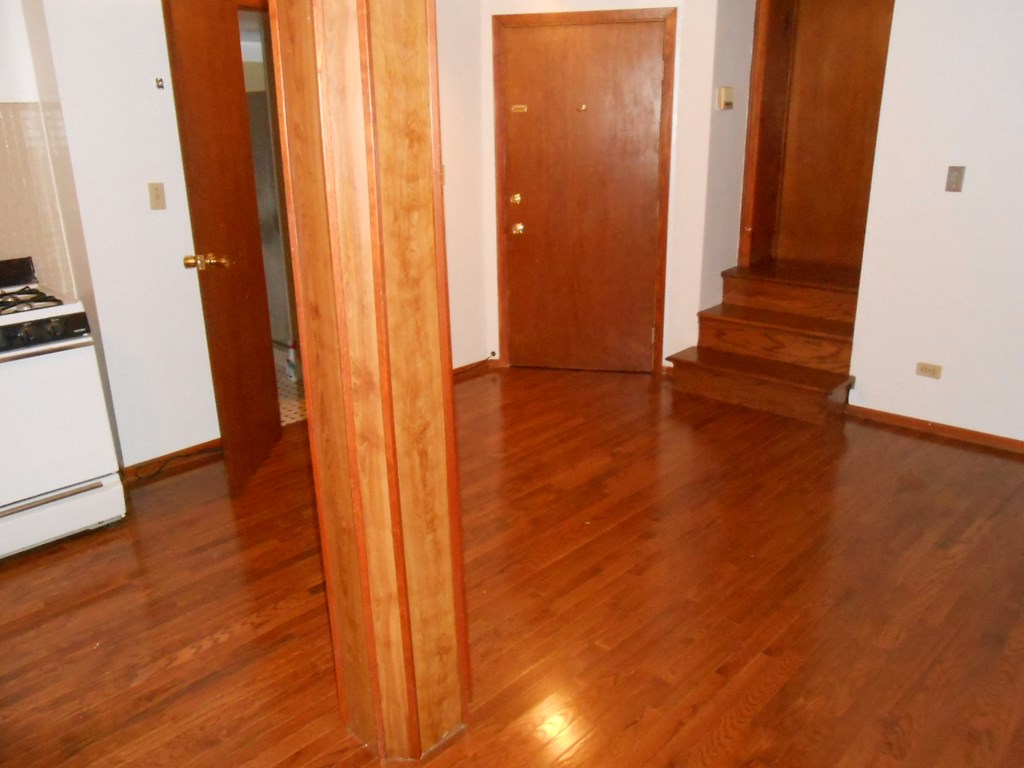 a living room and a hallway with wood floors and a wooden door