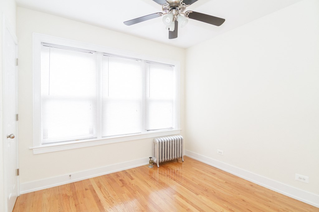 an empty room with a ceiling fan and two windows