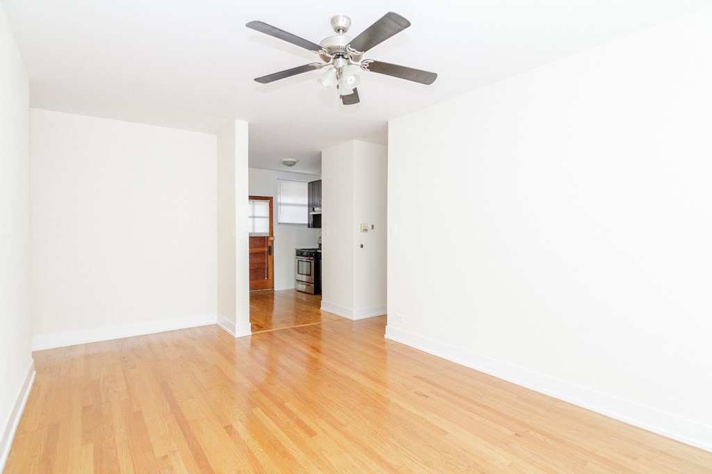 an empty living room with white walls and a ceiling fan