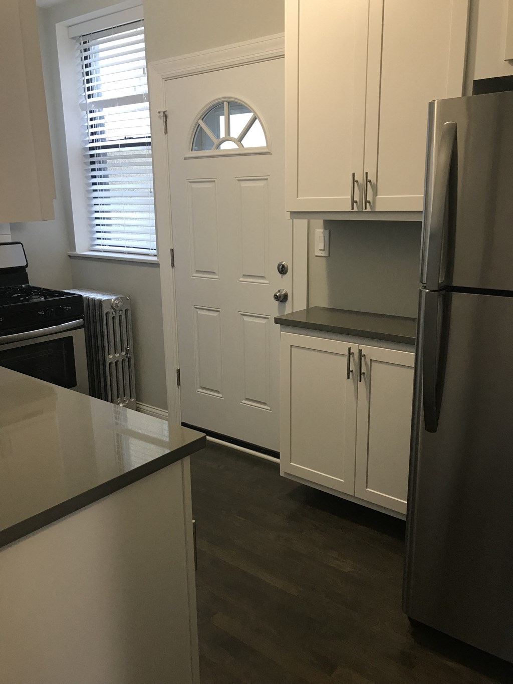 a kitchen with white cabinets and a door with a window