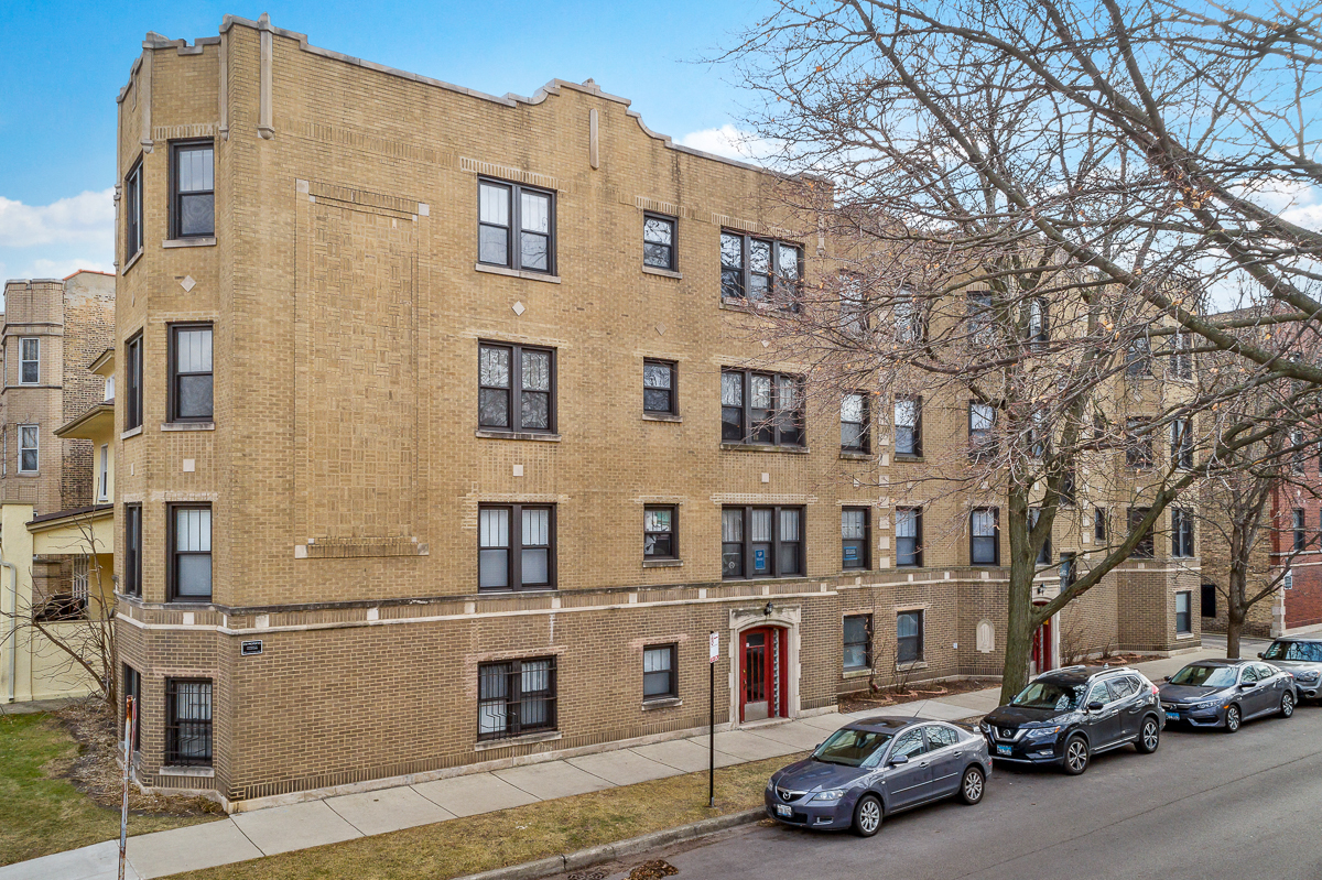 a brick apartment building with cars parked in front of it