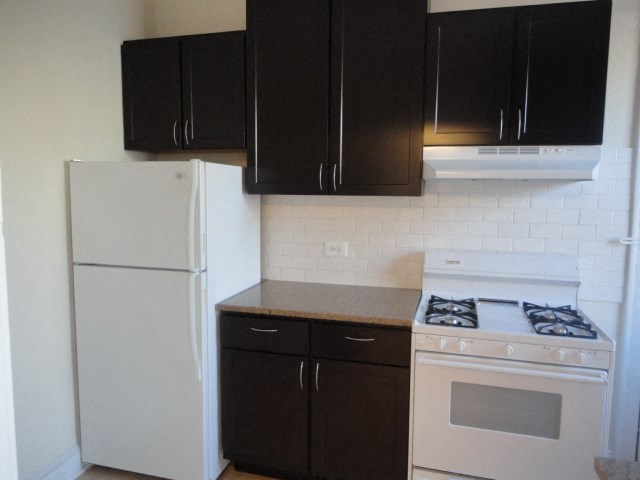 a kitchen with black cabinets and white appliances and a refrigerator