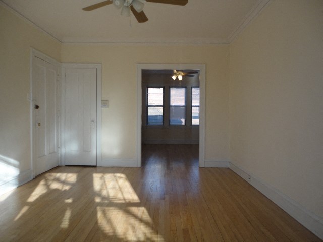 an empty living room with wood floors and a ceiling fan